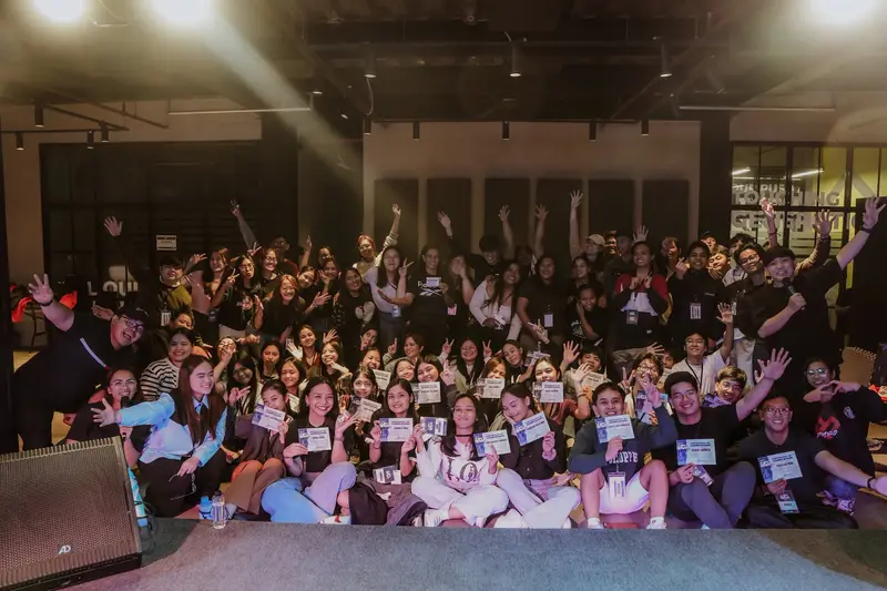 A packed hall of young people seated together for a group photo